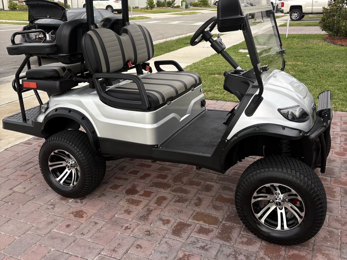 Silver lifted golf cart detailed on a brick driveway