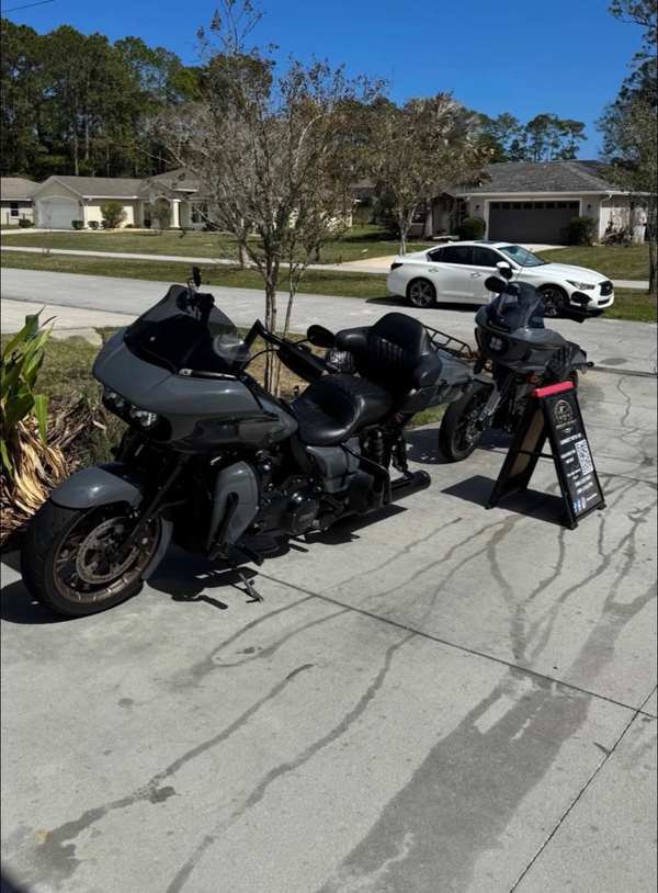 Two Harley-Davidson motorcycles being detailed side by side on a driveway