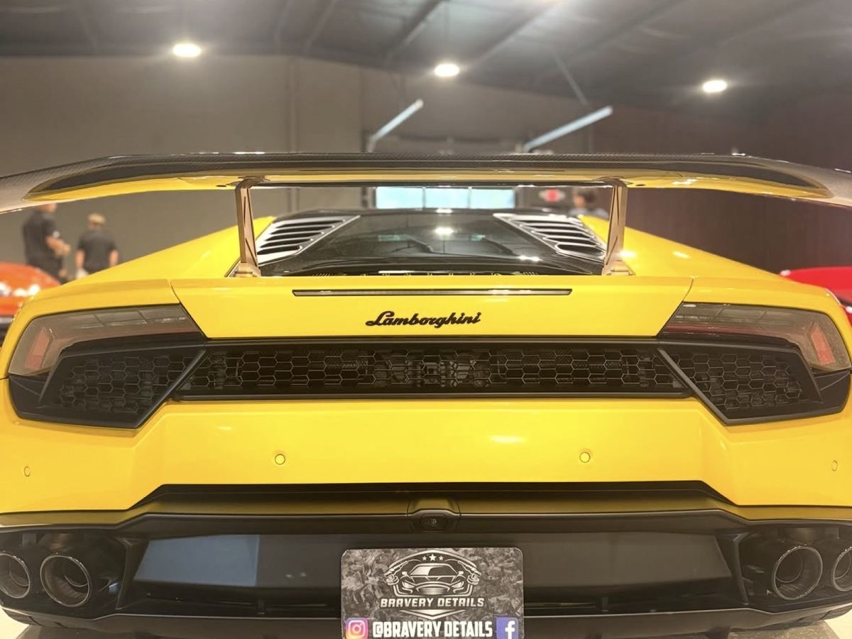 Yellow Lamborghini Huracán from the rear in a showroom, wearing a Bravery Details plate