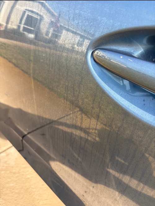 Close-up of a Mazda 3 door before paint enhancement — swirl marks and haze visible in daylight