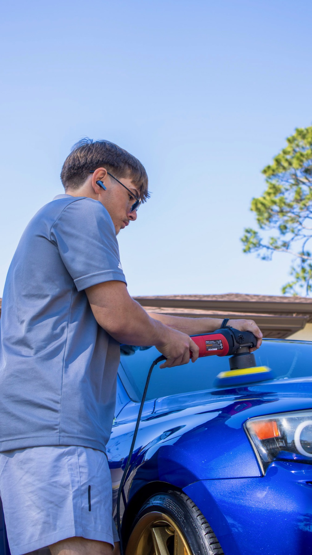 Machine polishing the hood of a blue Lexus during paint correction