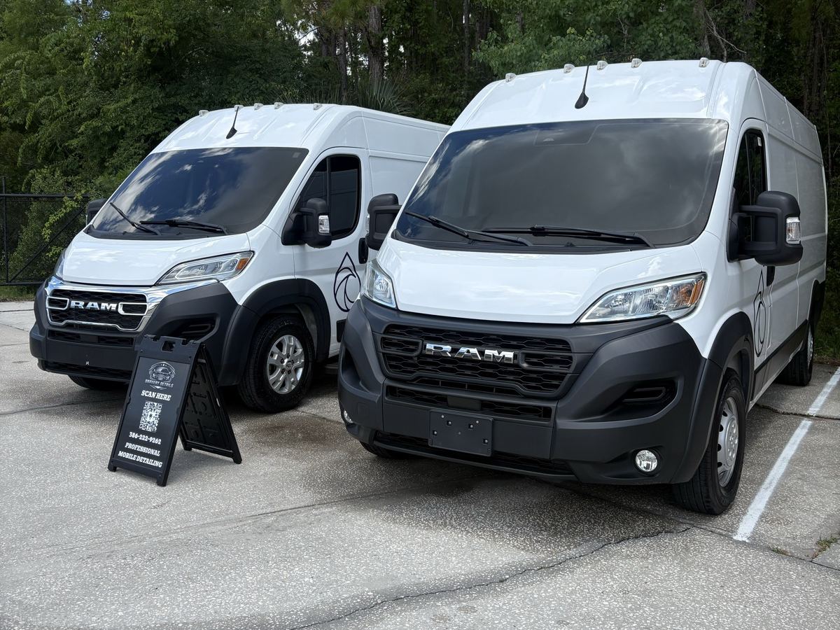 Two white Ram ProMaster work vans detailed side by side, Bravery Details sign in front