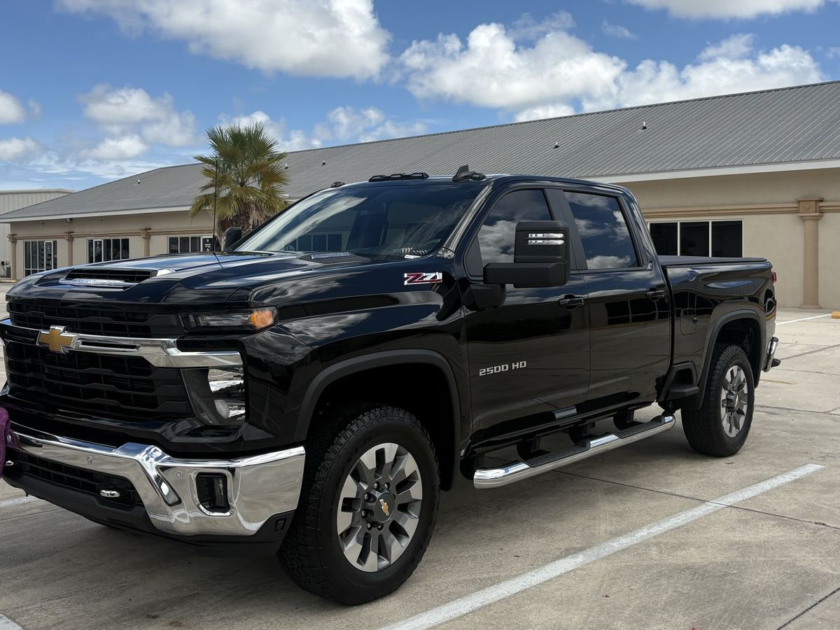 Black Chevy Silverado HD pickup detailed in a parking lot under a blue sky