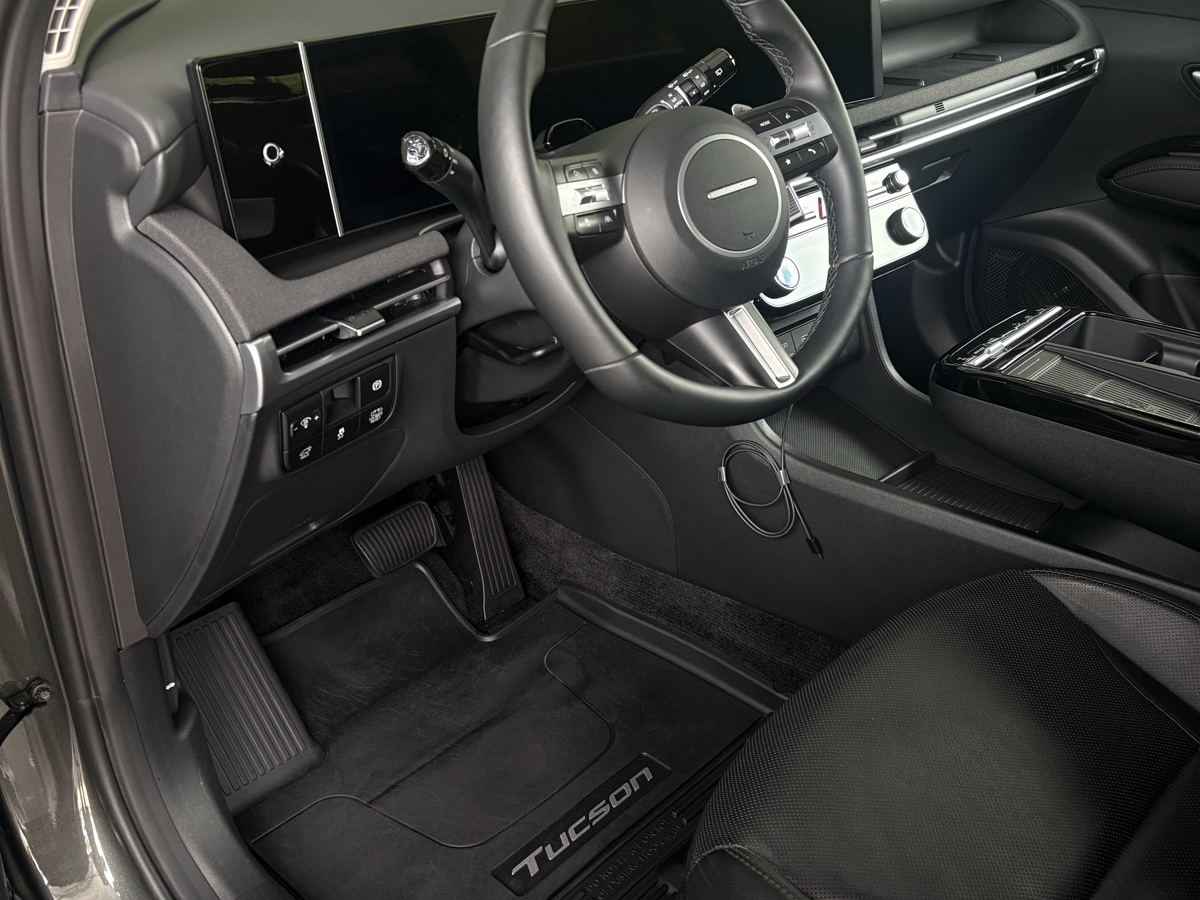 The same Hyundai Tucson footwell after detailing — mat vacuumed and scrubbed black again, trim wiped down